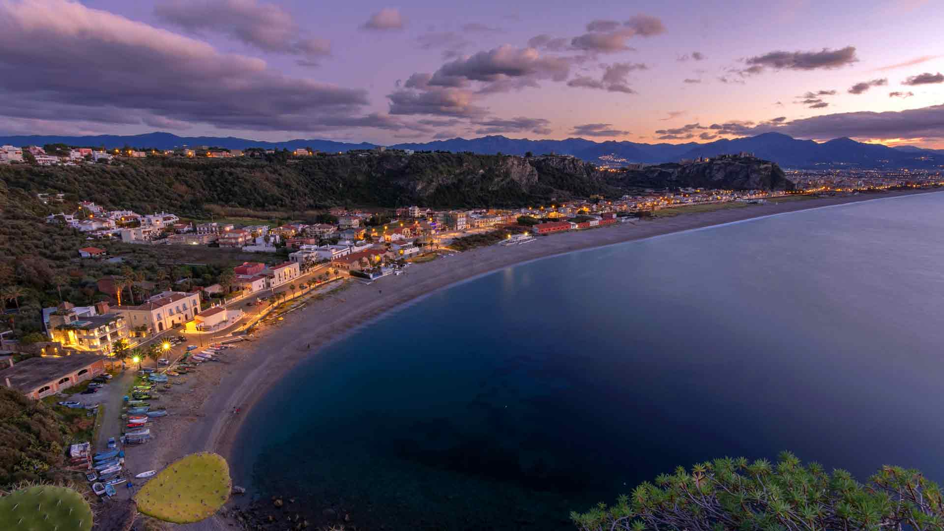 沿海小镇，灯光璀璨，黄昏宁静的海岸海滩