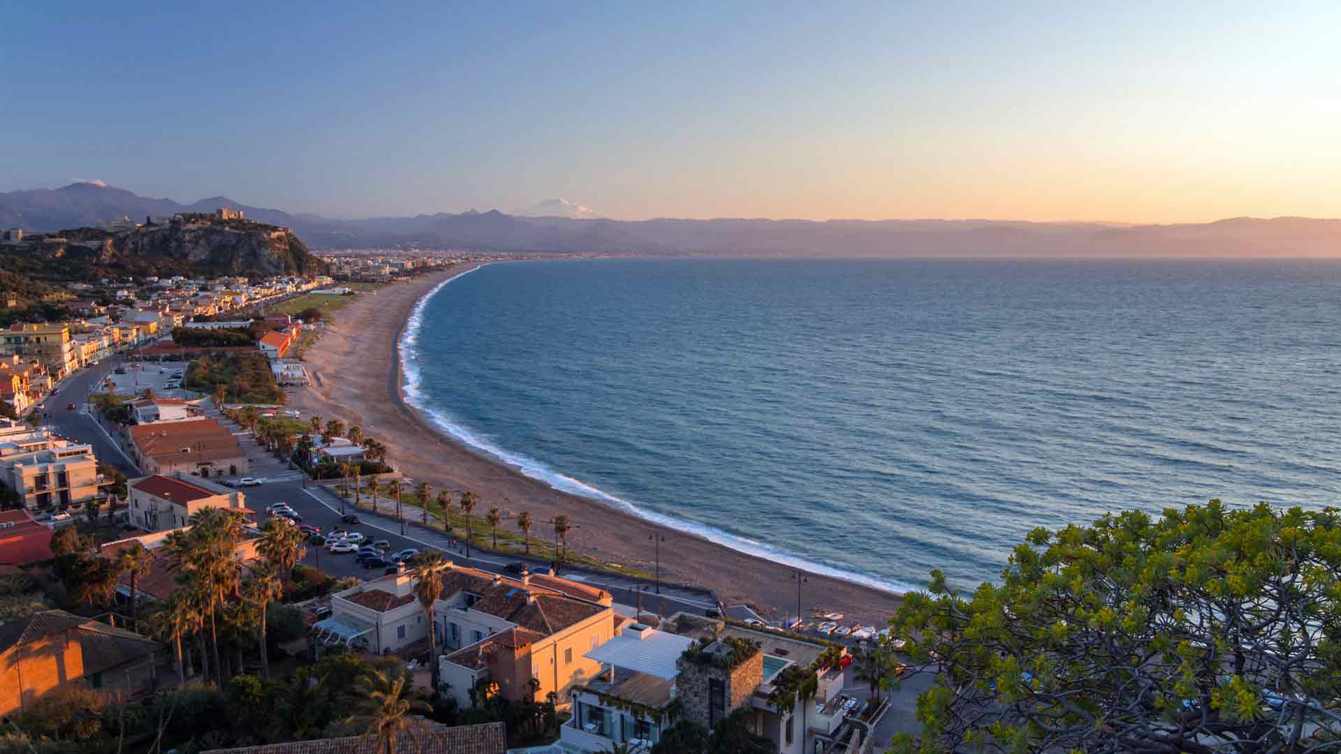 海滨小镇灯火通明，黄昏时分海面平静，夏日美景